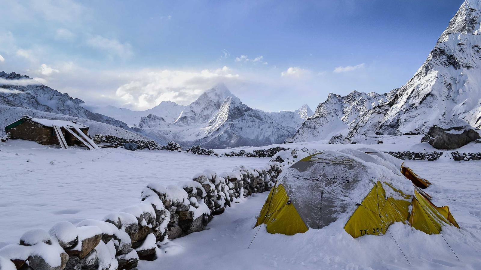 A yellow tent at a snowy mountain base camp (stock photo)